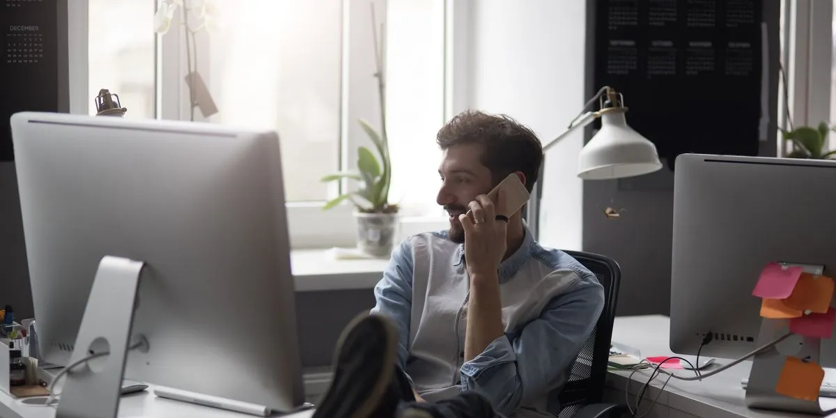 Jovem estudante a falar ao telefone enquanto trabalha no computador