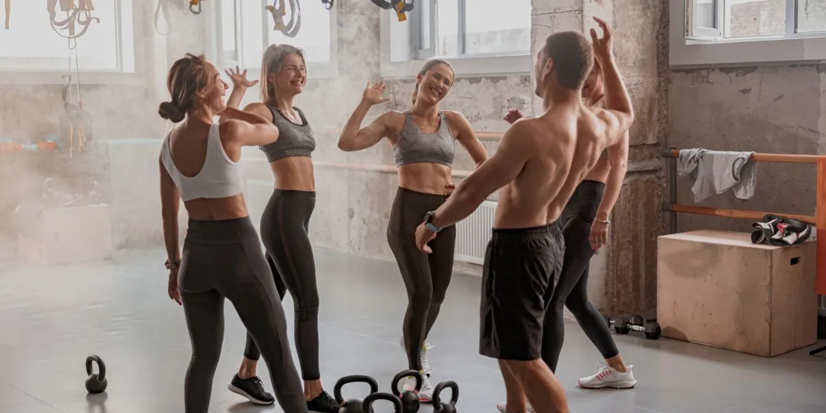 Grupo de treino no ginásio que acaba de terminar a sessão e batem as mãos alegremente