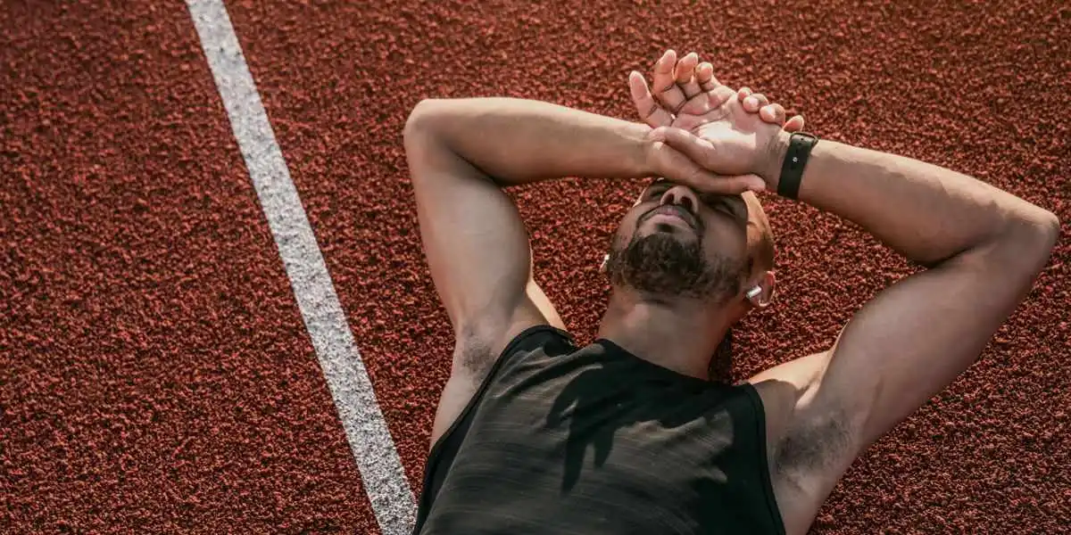 Atleta caído na pista de atletismo com sinais claros de falta de energia Atleta caído na pista de atletismo com sinais claros de falta de energia