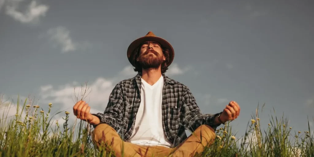 Homem com barba a meditar no campo