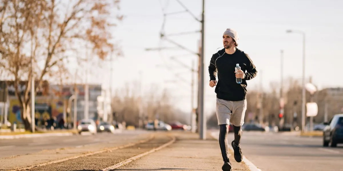 Corredor com garrafa de água na mão e boné