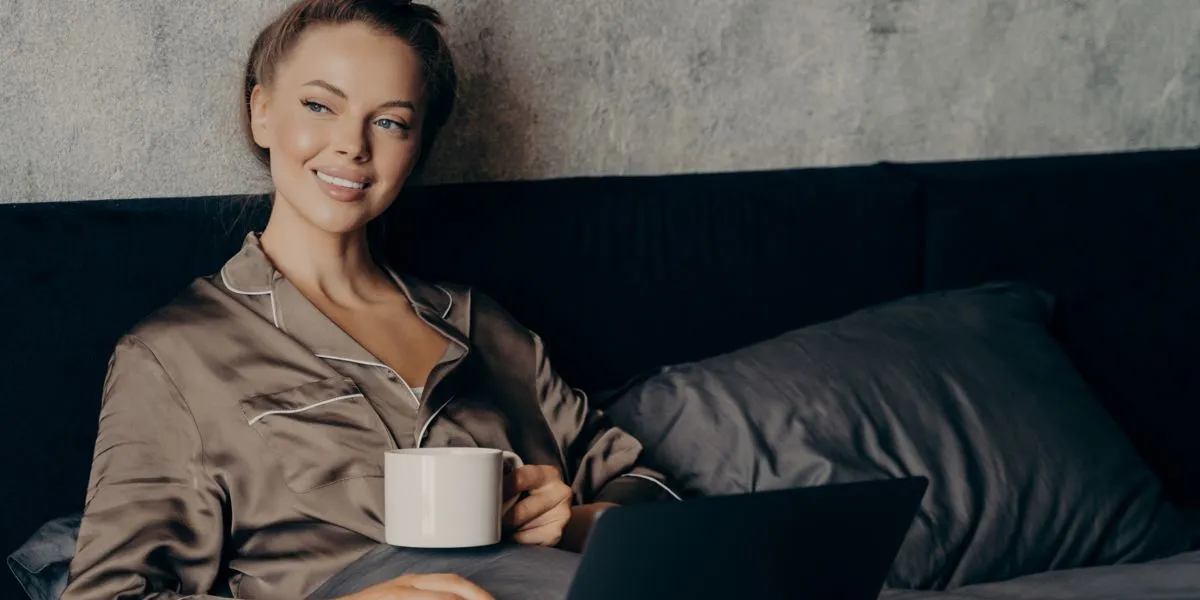 Mulher jovem em convalescença, a repousar na cama enquanto toma chá