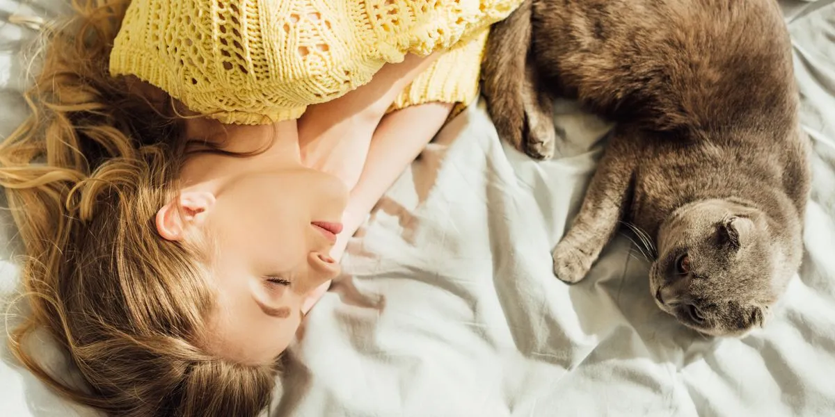 Mulher deitada na cama a descansar ao lado do seu gato